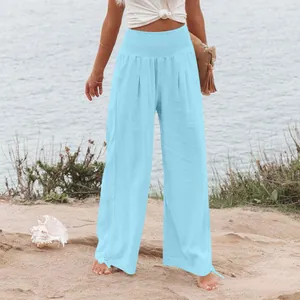 Pantaloni larghi in lino celeste a vita alta da donna su una spiaggia