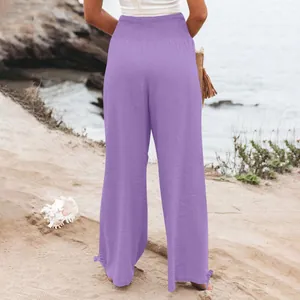 Vista posteriore di pantaloni larghi viola da donna con vita alta elastica sulla spiaggia.