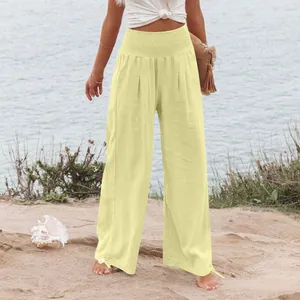 Modella che indossa pantaloni di lino a gamba larga giallo pallido sulla spiaggia