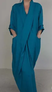 Detail view of a teal blue V-neck maxi dress with large side pockets and rolled sleeves.