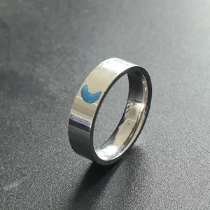Detailed close-up of a stainless steel ring featuring a luminous blue moon inlay design