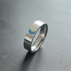 Close-up of a stainless steel ring featuring a blue luminous crescent moon inlay.