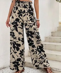 Détail d'un pantalon large à imprimé fleuri avec une taille haute élastiquée et smockée