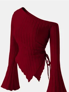 Close-up of burgundy ribbed knit top with asymmetric hem and flare sleeves