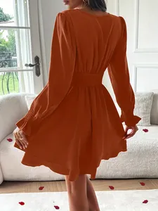 Vue arrière d'une robe orange à manches longues avec taille élastique et ourlet étagé.