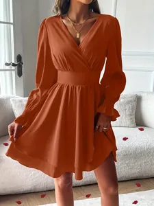 Gros plan sur une robe orange à col en V avec ourlet double couche et taille cintrée