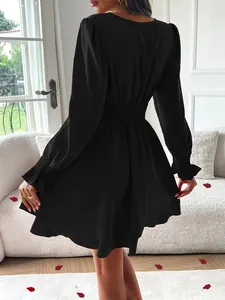Robe élégante noire à manches longues, col en V, taille smockée et détails de jupe à couches.