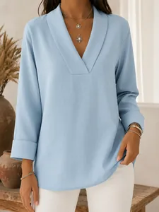 Detail view of light blue V-neck blouse with shawl collar and nine-quarter sleeves