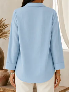 Detailed back view of a light blue loose-fit shirt with curved hem and folded cuff details
