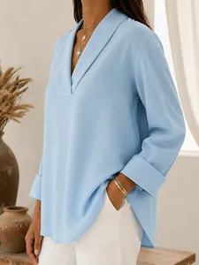 Close-up of a light blue V-neck shawl collar blouse with elegant folded cuffs.