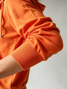 Primo piano di un cardigan in maglia con cappuccio arancione con polsini a coste