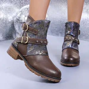 Detailed view of brown western ankle boots with iridescent floral embossing and buckles.