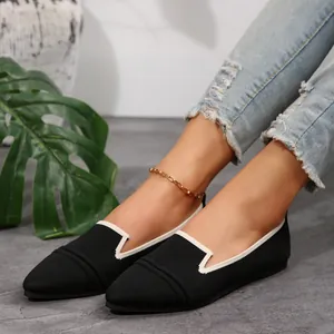Close-up view of black pointed-toe flying weave flat shoes with white trim worn by a model