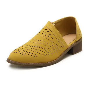 Macro view of yellow laser-cut pointed-toe low chunky heel shoes with ethnic style