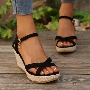 Close-up of black cross strap wedge sandals with woven platform and ankle buckle