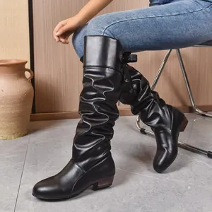 Primer plano de botas altas negras para mujer con un elegante lazo de cinta en la espalda.