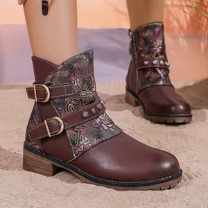 Detailed view of maroon western boots with floral embossed pattern and buckles.