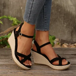Stylish black crisscross wedge sandals with woven platform and dainty ankle strap charm.