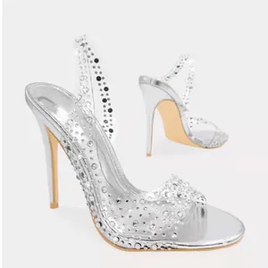 Détail d'élégantes sandales à talons aiguilles argentées avec brides transparentes à strass.