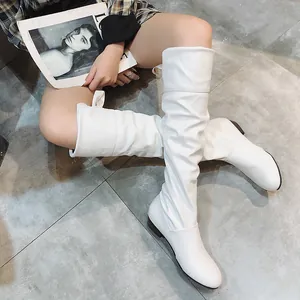 Detalle de botas altas blancas con diseño arrugado, tacón bajo y cordones traseros