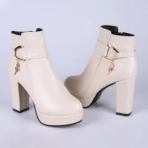 Vue détaillée des bottines beiges à talons épais avec une breloque M en métal doré