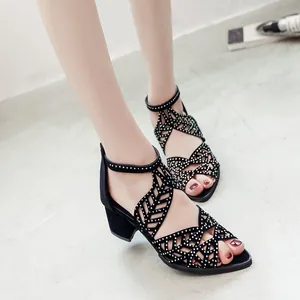 Close-up of black peep-toe cutout sandals with rhinestone details and block heel.