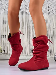 Close-up of red suede slouchy mid-calf boots with tie-back detail on model's legs