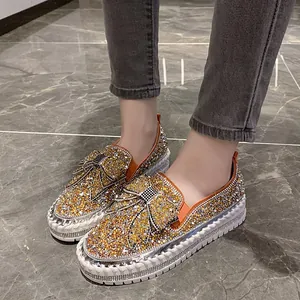 Gros plan de mocassins étincelants avec nœud en strass dorés et semelles blanches
