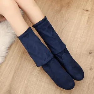 Primo piano di eleganti stivali morbidi in pelle scamosciata blu navy con design risvoltato.