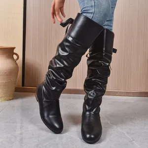 Vista detallada de las botas negras altas con pliegues y lazo en la parte posterior