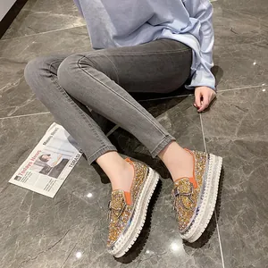 Détail de chaussures à plateforme à strass dorés scintillants avec un nœud orange