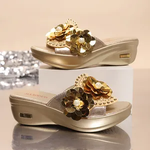 Close-up of golden bohemian wedge sandals with sequin flowers and pearls