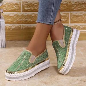 Primo piano di mocassini verdi con zeppa e strass indossati per un look casual trendy