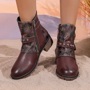 Detail of vintage floral embossed leather ankle boots with chunky heel on sand background