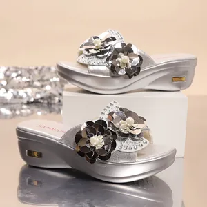 Detailed close-up of silver bohemian wedge sandals with sequin flower decorations
