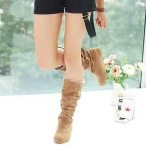 Detailed shot of tan suede mid-calf boots featuring elegant lace trim and a slouchy design