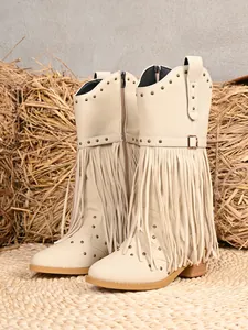 Detail view of beige Western cowboy boots featuring layered fringe and metal stud accents