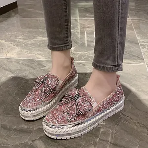 Détail de mocassins roses scintillants avec nœud en strass et semelle compensée