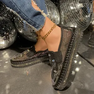 Detail of black mesh platform loafers with sparkly rhinestones and gold anklet decoration.