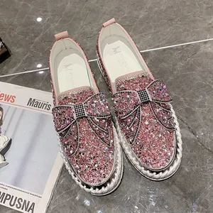 Détail de mocassins roses à paillettes avec gros nœud en strass et semelle épaisse