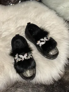 Detailed view of black loafers featuring sparkling butterfly rhinestones and plush fur trim