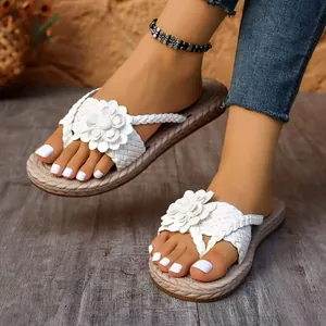 Detailed view of elegant white floral flip-flops with braided straps on model's feet.