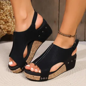 A close-up shot of black wedge platform sandals featuring cork soles and rivet details