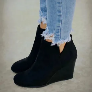 Seitenansicht schwarzer Wildleder-Keilstiefeletten mit modischen Fransen-Jeans kombiniert
