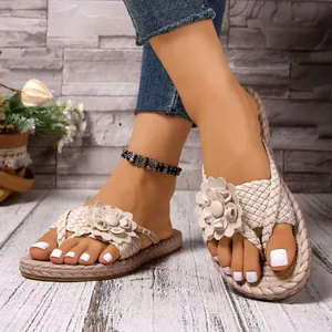 Close-up detail showing the intricate braided texture and flower of women's beige toe-loop sandals