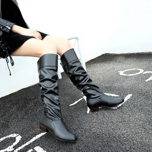 Close-up view of black slouchy knee-high boots with pleated texture and a round toe.