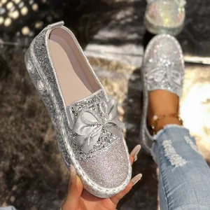 Close-up of elegant sparkly silver loafers featuring rhinestone bow and glitter finish