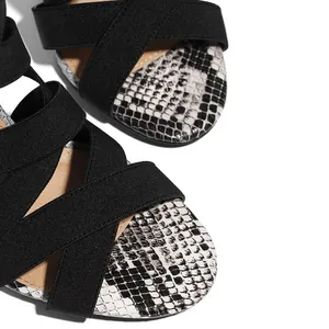 Macro view of sexy Roman sandals featuring black cross-straps and snake pattern details