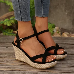 Close-up view of elegant black wedge sandals with cross straps and a woven espadrille heel