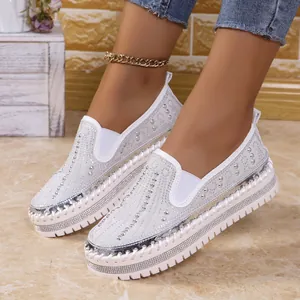 Dettaglio ravvicinato di mocassini bianchi con strass e suola spessa platform